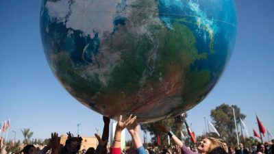 Members of International delegations play with a giant air globe ball outside the COP22 climate conference on November 18, 2016, in Marrakesh. / AFP PHOTO / FADEL SENNA